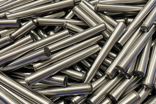 Polished steel cylindrical pins. Shiny machined components. Industrial manufacturing background. Smooth silver surfaces. Precision engineering parts. Metalworking material. Steel workpieces.