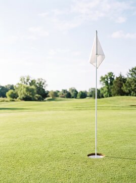White flag marking a hole on a lush green golf course green
