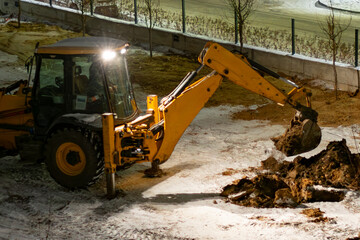 An excavator digs a trench at night under floodlights © Anton Vakhrushev