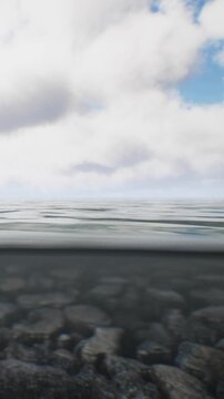 The view shows the surface of water with gentle ripples. Clouds drift above in the sky. The scene is calm and open with a distant horizon.