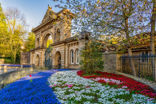 A stunning HDR photograph capturing the magnificent Victorian entrance gateway to Corporation Park, Blackburn, Lancashire, in full spring splendour. The ornate sandstone arch dominates the composition