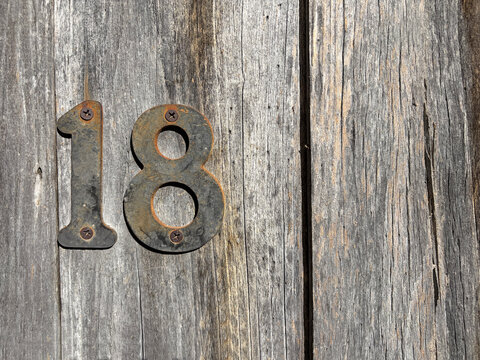 n&uacute;mero 18 met&aacute;lico en una puerta de madera antigua IMG_8884-as26