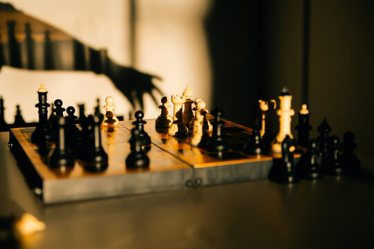 Chess board with pieces in dramatic golden sunlight
