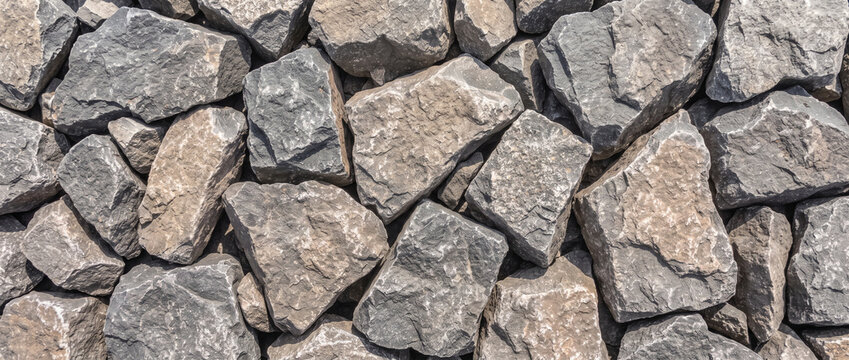 Stone riprap texture background of jagged grey rocks and boulders