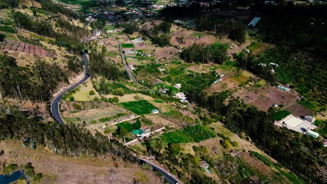 Drone footage presents a broad Andean countryside in Tungurahua, Ecuador, where green and brown farm plots, scattered homes, narrow roads and wooded hills form a patchwork beneath a vast, heavily clou