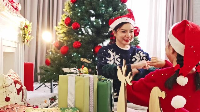 Mother and Daughter Sharing Christmas Gifts Beside Festive Tree