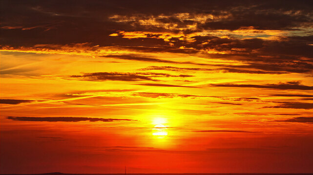 Aerial view of a vibrant sunset with golden and orange clouds stretching across the horizon in Latvia.