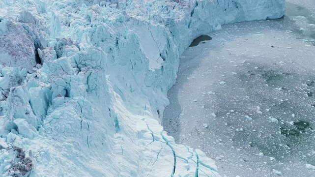 Aerial view of the massive blue icebergs and jagged glacier walls of the Ilulissat Icefjord in Ilulissat, Avannaata, Greenland.