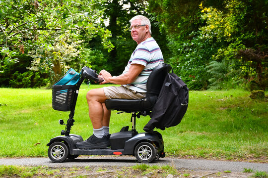 Middle aged man enjoying being outdoors in summer using his mobility scooter to get out and about despite his health issues.which prevent him walking .