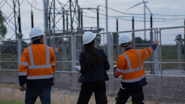 Engineering team examines electrical substation equipment during a field inspection, representing power grid maintenance, infrastructure assessment, workplace safety and utility reliability.