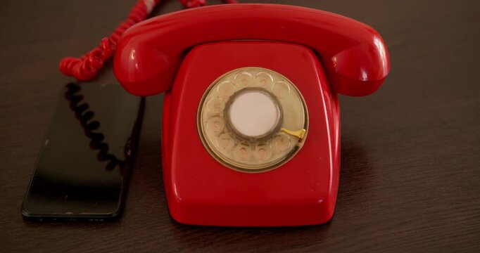 Vintage Rotary Phone and Modern Smartphone: A classic red rotary telephone sits beside a sleek, dark smartphone.