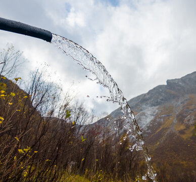 View of a clear stream of water flowing with visible droplets against a cloudy sky in Tafjord, More og Romsdal, Norway.