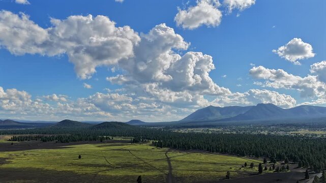 Aerial view of Cinder Hills and Elden Mountain with green forest floor and dramatic clouds in Flagstaff, Arizona, United States.