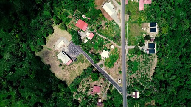 A broad aerial view looks across dense green forest, rolling hills, fields and a small settlement connected by roads in Ecuador&rsquo;s Oriente. Layered hills meet a distant horizon beneath a sky filled wit