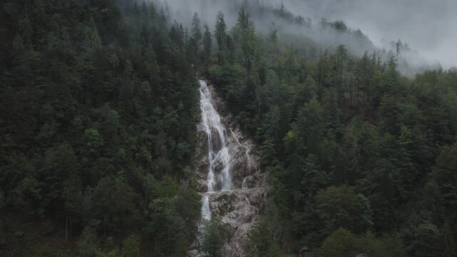 An aerial of the Plesnik waterfall with clouds and trees surrounding it, Logarska Dolina, Slovenia 
