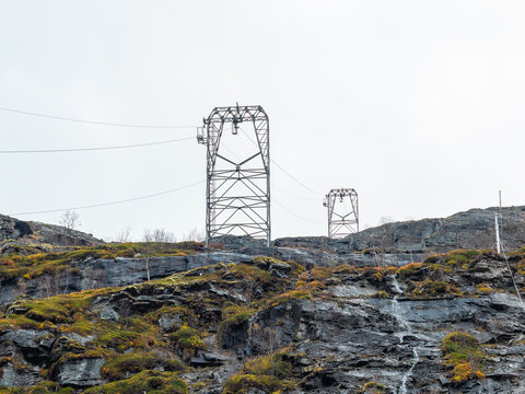 Aerial view of industrial cableway towers standing on a steep, rocky, moss-covered mountainside in Tafjord, More og Romsdal, Norway.
