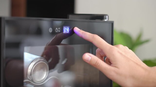 Hand adjusting wine cooler temperature using digital touch panel