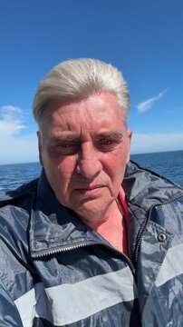 Portrait of mature deck officer on boat deck, sea view background, professional senior mariner during sunny navigation voyage.