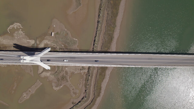 Aerial view of the Arade Bridge spanning the river with vehicles crossing the cable-stayed structure, surrounded by mudflats and water in Portimao, Faro District, Portugal.