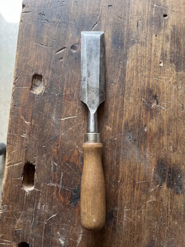 Worn steel wood chisel on a wooden workbench