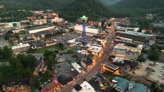 Gatlinburg, Tennessee at night with Parkway street lined with restaurants, attractions and shops for visitors. Appalachian hills surrounding American vacation town.