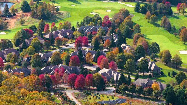 Hillside homes surrounded by colorful woodland. Rolling mountain terrain creates beautiful residential landscape in autumn.