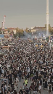 A vertical video wide view of a large crowd of people at the Octoberfest grounds in Munich, Germany