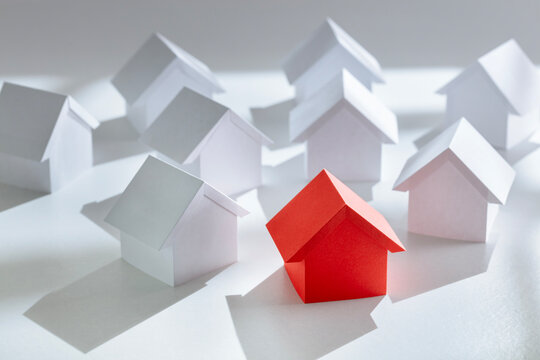Searching for real estate property red paper house standing out from background houses