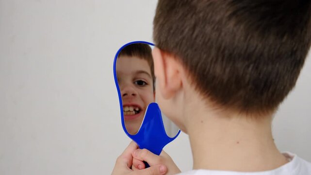 A child at the dentist's office examining his teeth in a mirror. Selective focus.