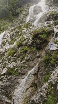 A vertical video of the Plesnik waterfall and trees surrounding it, Logarska Dolina, Slovenia 