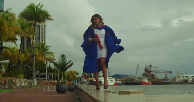 Young woman holding a graduation certificate with pride outdoors during evening light.