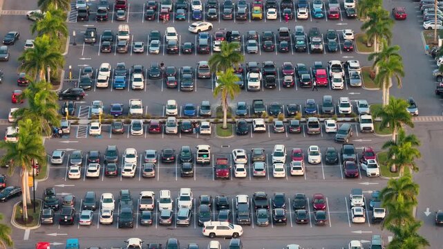 Shopping mall with extensive car parking area and dense vehicle arrangement, illustrating high consumer demand, supply chain flow and economic movement.