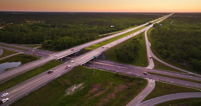 Wide multilane expressway crossroad with overpass ramps and flowing traffic in rural American landscape