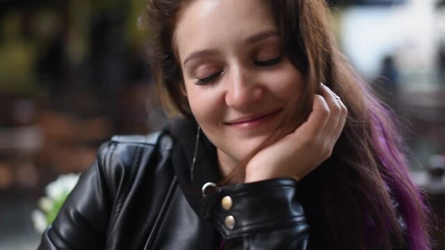 Flirting and first date at street cafe for dating ads, shy young woman with long hair rests chin on hand in old town, close up. Flirting shy smile, woman laughs and shyly looks away