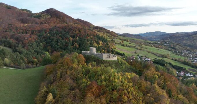 Aerial pullback from Rytro Castle ruins over autumn hills and valley