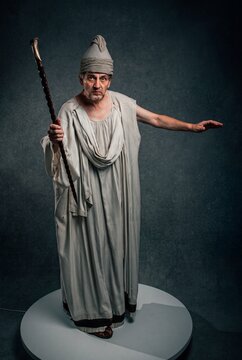 Ancient religious figure in a classical robe holding a staff in a studio portrait