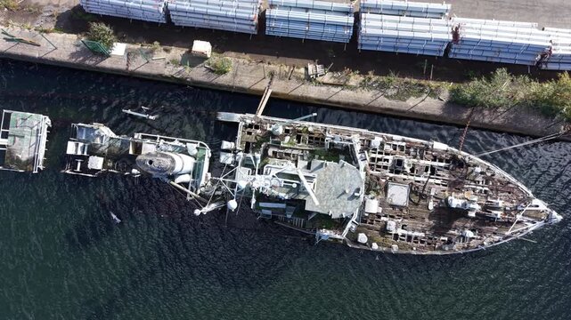 Aerial drone 4K scene showing HMS Bronington sitting partially submerged with visible structural decay glowing under warm daylight UK