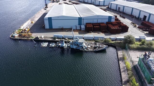 Aerial drone 4K view of HMS Bronington partially submerged and deteriorating in warm daylight