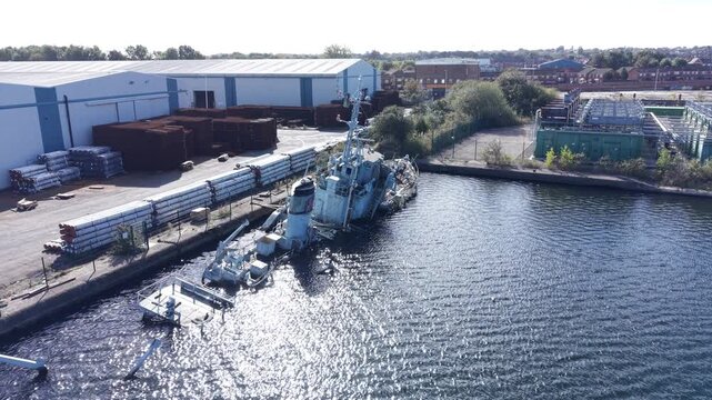 Aerial drone 4K footage showing HMS Bronington resting in deteriorated sinking condition illuminated by warm sunlight with bright natural tones UK