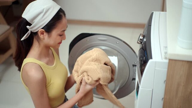Housewife taking freshly washed clothes from a washing machine and enjoying their clean, fresh scent, highlighting laundry care, detergent, fabric softener. Household chores concept.
