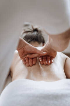 Professional masseuse giving back massage to woman at health spa