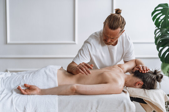 Man giving woman a back massage on a table in a spa