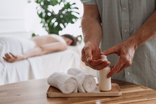 Man dispensing essential oil for therapeutic body massage procedure