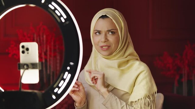 Arab woman in hijab recording video on phone for her social media content