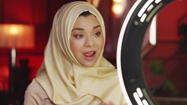 Happy Middle Eastern woman in hijab recording lifestyle video blog on phone