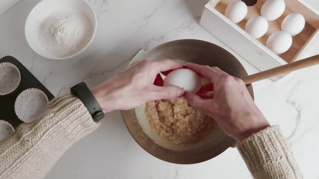 Hands of a woman cracking an egg into a bowl. 