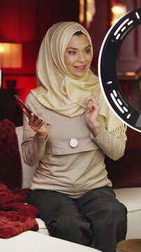 Happy Muslim business coach recording financial video blog on phone at home