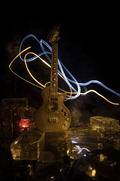 Music Concept: Guitar Miniature on a Dark Background with Vivid Light, Smoke, and Fire Effects. Golden electro guitar under a Dramatic Spotlight.