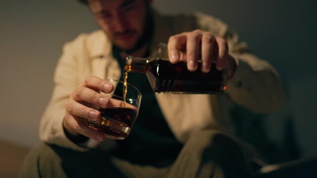 Lonely adult male copes with emotional heartbreak holding amber whiskey. Acute personal despair