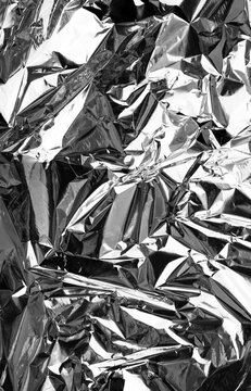 Crumpled silver foil texture, close up shiny metallic background pattern.